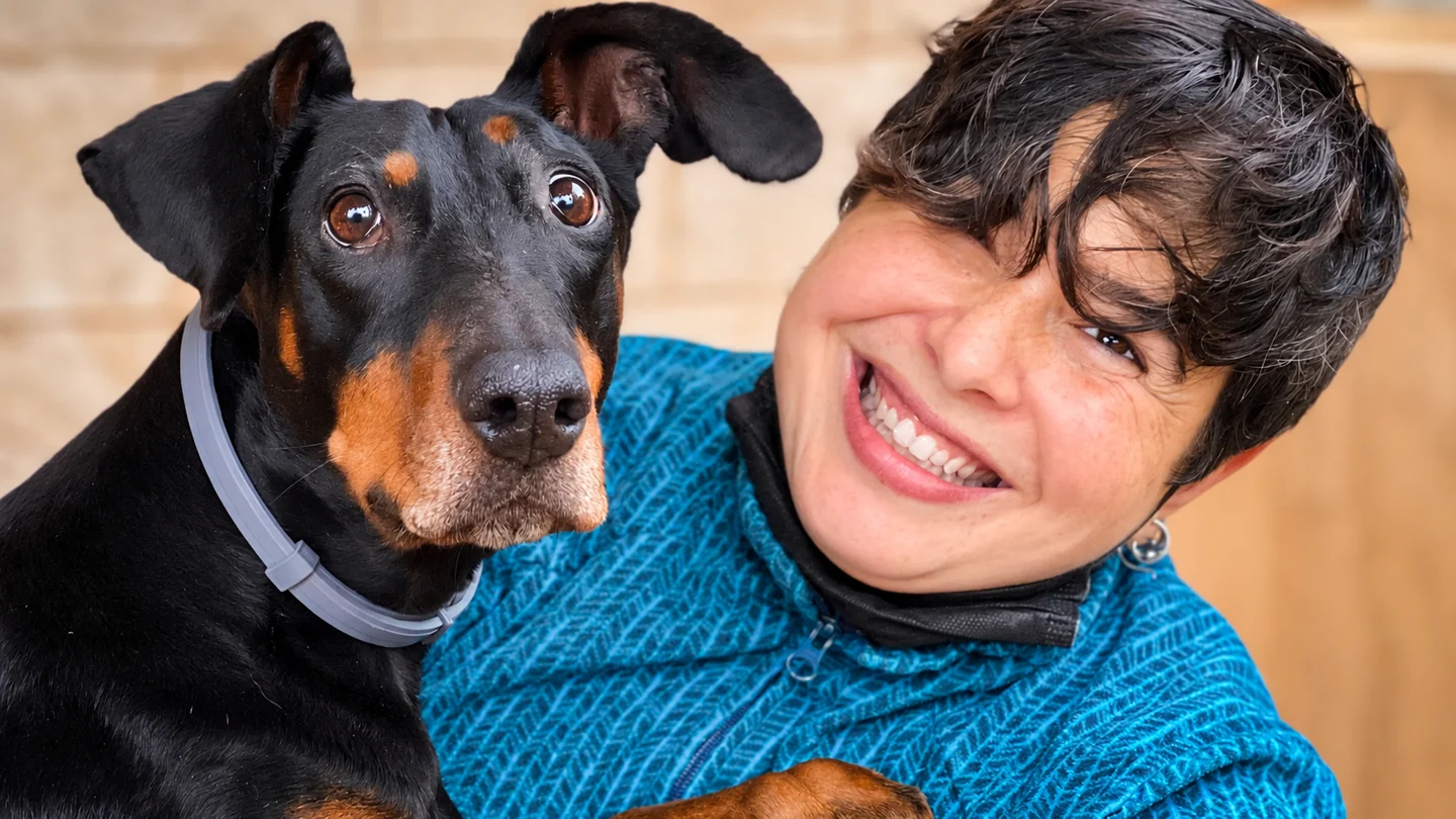 Maribel smiling with a black dog